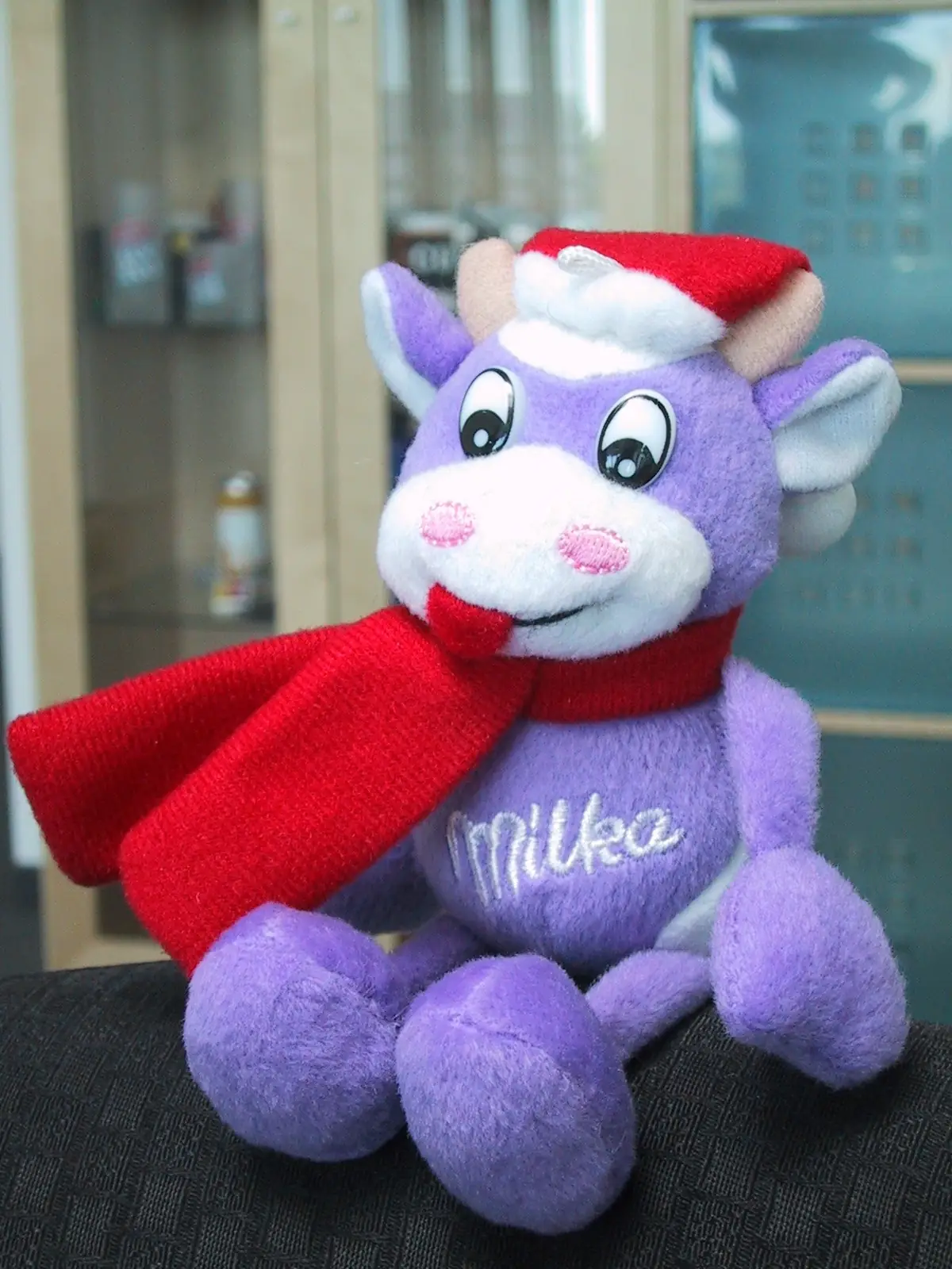 MILKA Winterkuh als Plüschtier mit rotem Schal und Weihnachtsmütze in Markenfarbe